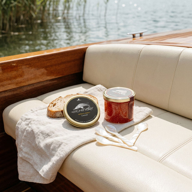 Caviar Imperial Baerii, œufs de truite Red Pearl et cuillères en nacre sur du lin à bord d'un bateau classique en bois