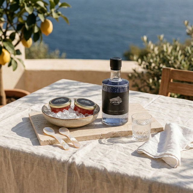 Red Pearl trout roe, Red Pearl Caviar Vodka, a glass and mother-of-pearl spoons on a sunlit stone terrace by the lake