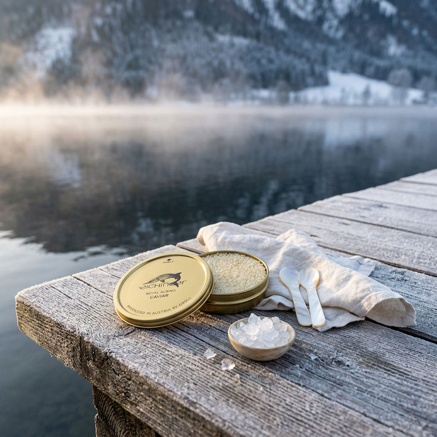 Open tin of Eichinger Royal Albino caviar with two mother-of-pearl spoons on a frosted jetty by a misty Alpine lake