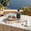 Red Pearl Forellenkaviar, Red Pearl Caviar Vodka, ein Glas und Perlmuttlöffel auf einer sonnigen Steinterrasse am See